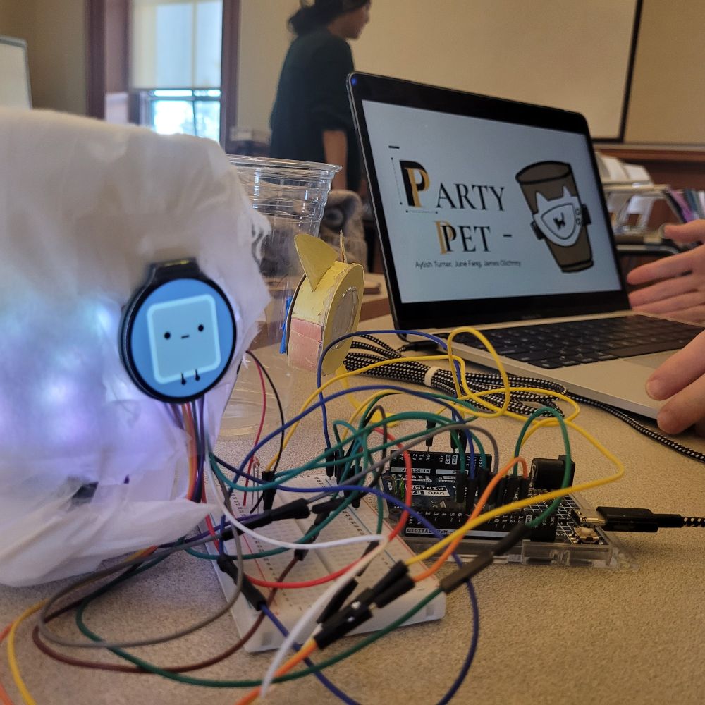 The Party Pet digital prototype, which is a Tamagotchi-like screen hooked onto a cup on the left with the Arduino and all of the wires. 