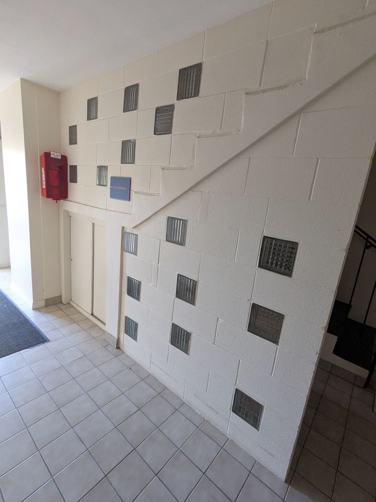 Stairwell wall at a hotel. The white-painted cinder block wall has glass blocks at seemingly random intervals.