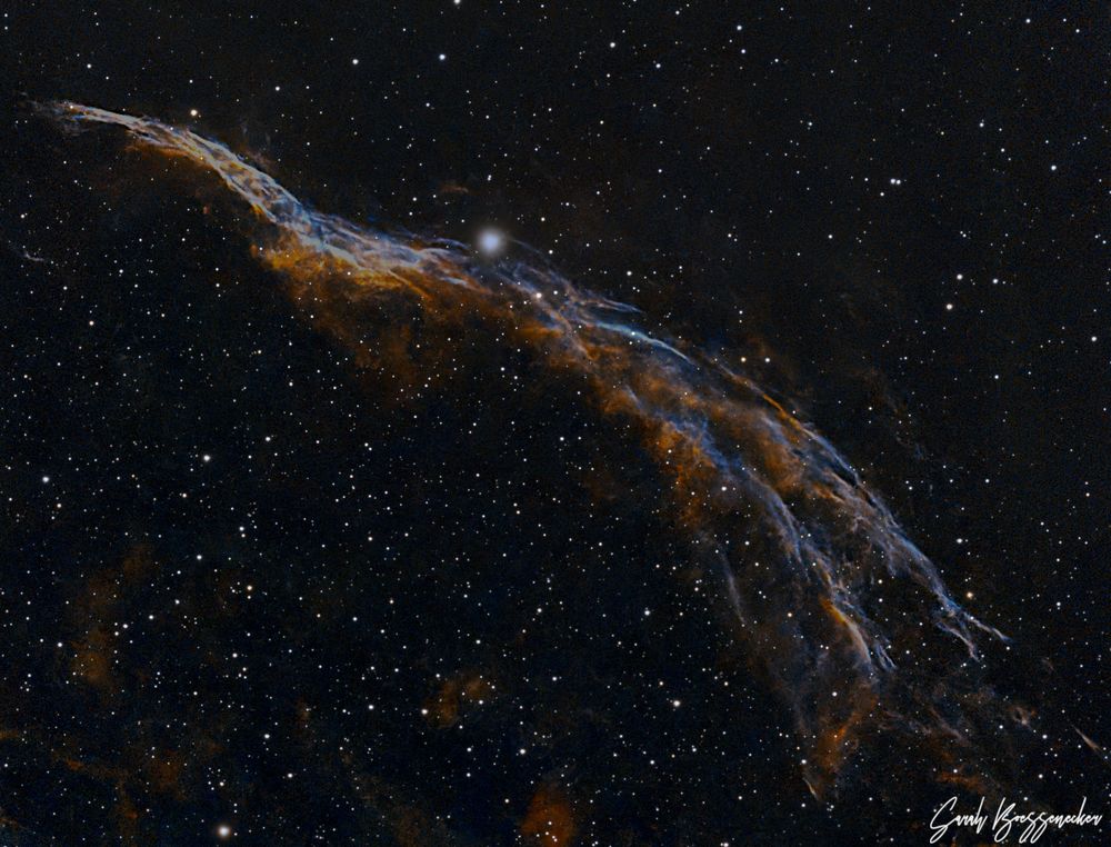 a wispy nebula in a field of stars that looks reminiscent of a witch's broom