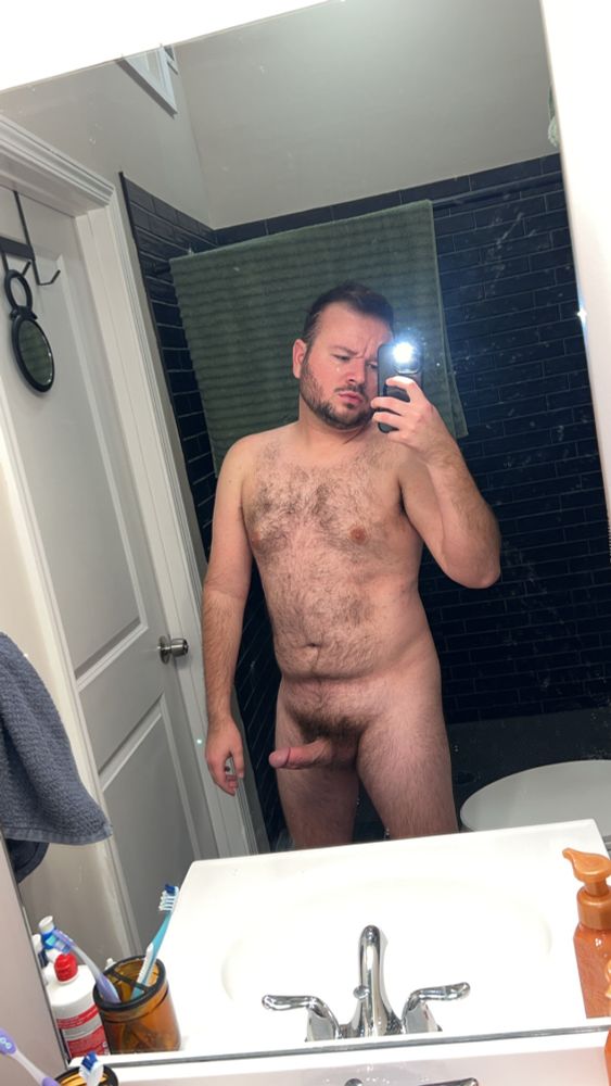Me, naked, standing in front of my bathroom mirror. Hairy body on display, with my cock stretching out from my thick bush. Horrible bed head. 