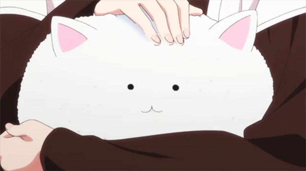 a person is petting a white stuffed animal with a cat face