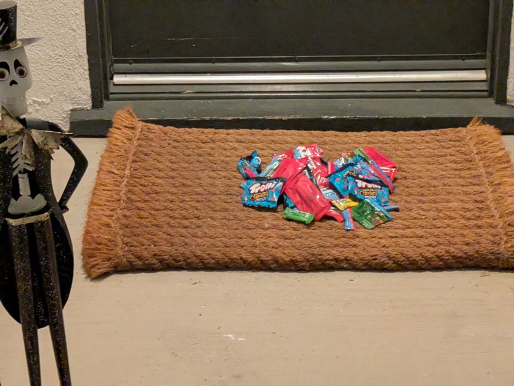 Photo of a doormat with a pile of candy in it.