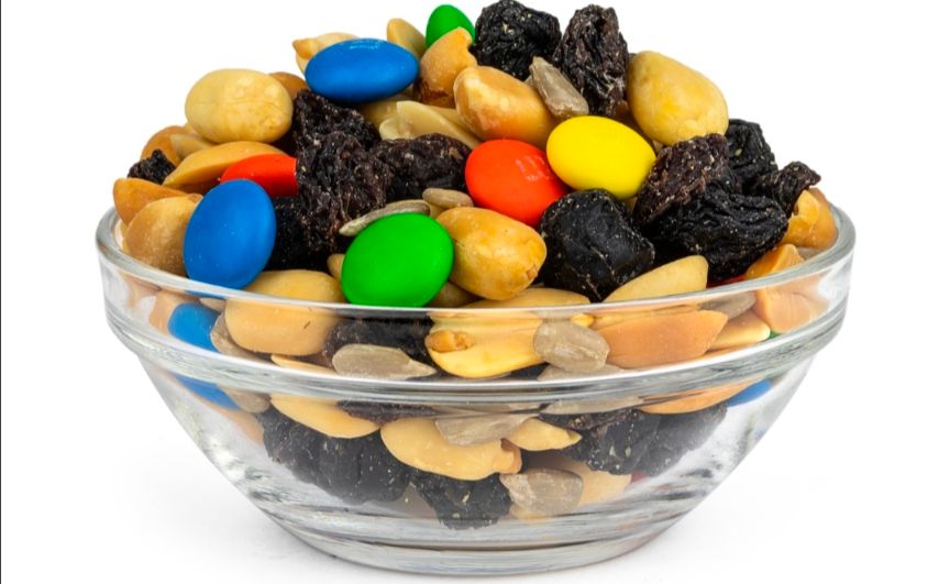 a stock image of a glass bowl of the trail mix GORP- good ol raisins n' peanuts- that also has m&ms and sunflower seeds