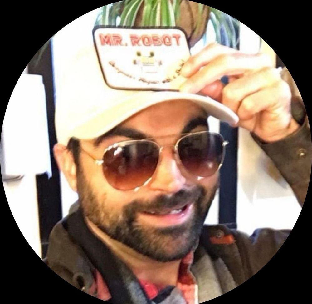 Greg's profile picture. A smiling man wearing sunglasses and a mr robot baseball hat