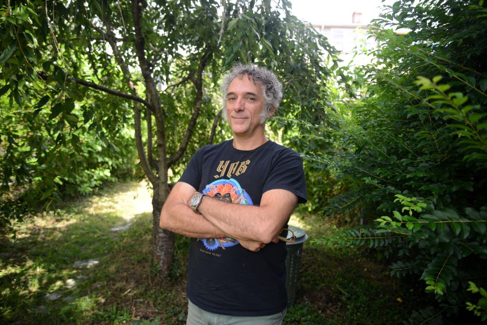 A man stands in a green backyard with trees in Washington, DC.