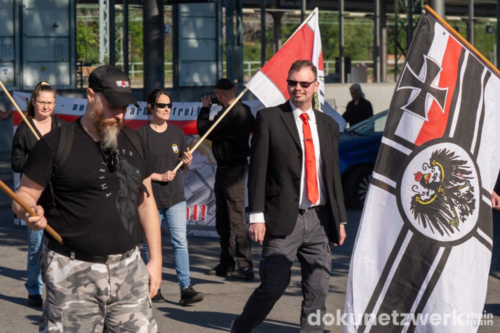 Im Vordergrund ist eine Kaiserreichsflagge zu sehen. Dahinter Teilnehmer der Neonazidemo
