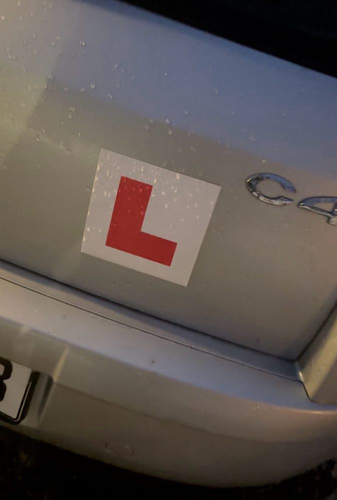 Baken på en grå bil med rød L klistret på