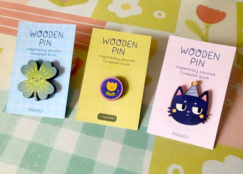 three wooden pins: clover, a little tulip and Skit the cat with a party hat