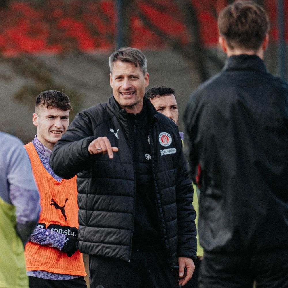 Alexander Blessin steht im Mannschaftskreis und gestikuliert.