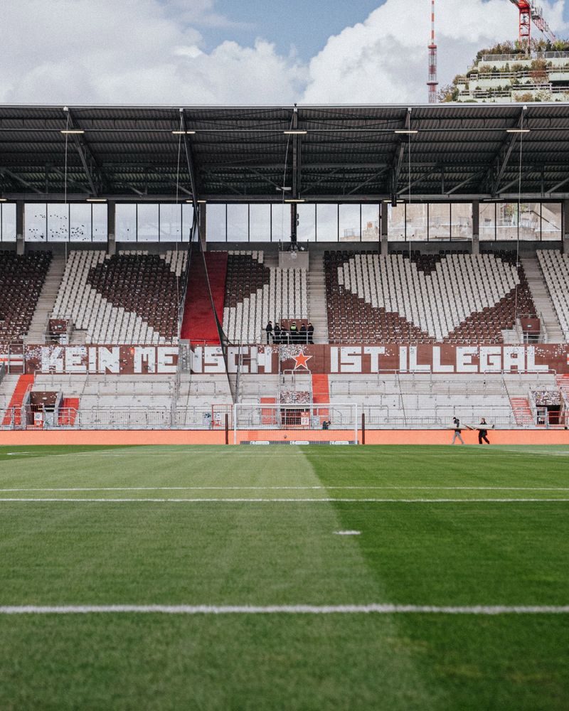 Blick auf die Nordtribüne im Millerntor-Stadion. Zu sehen sind zwei Herzen und der Schriftzug "Kein Mensch ist illegal".