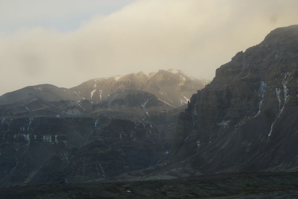 Southern Icelandic mountains, with little frozen waterfalls, and clouds gently touching the tops to make everything look misty and ethereal 