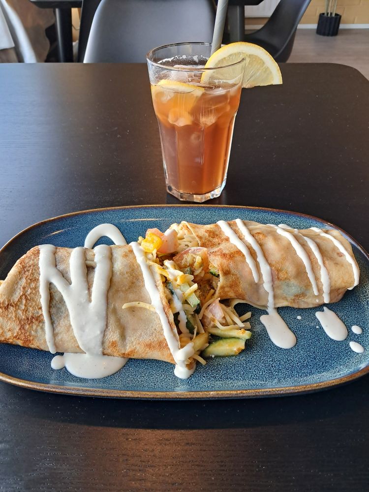 A thin pancake roll filled with savory stuffing, and a glass of lemon ice tea.
