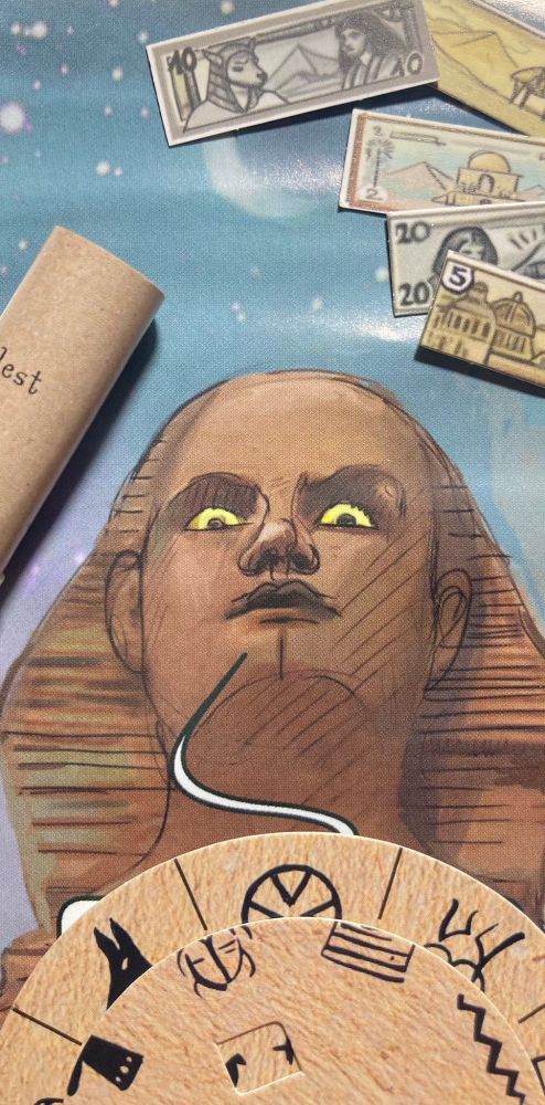 The head of the sphinx in the middle, to the left a "papyrus" scroll of paper, in the top right corner money bills, at the bottom part of a wheel with "hieroglyphs"