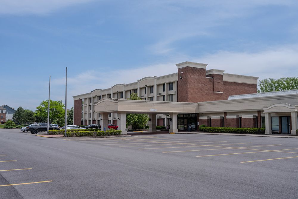 Exterior of a building that used to be a hotel with a covered entrance and brick structure