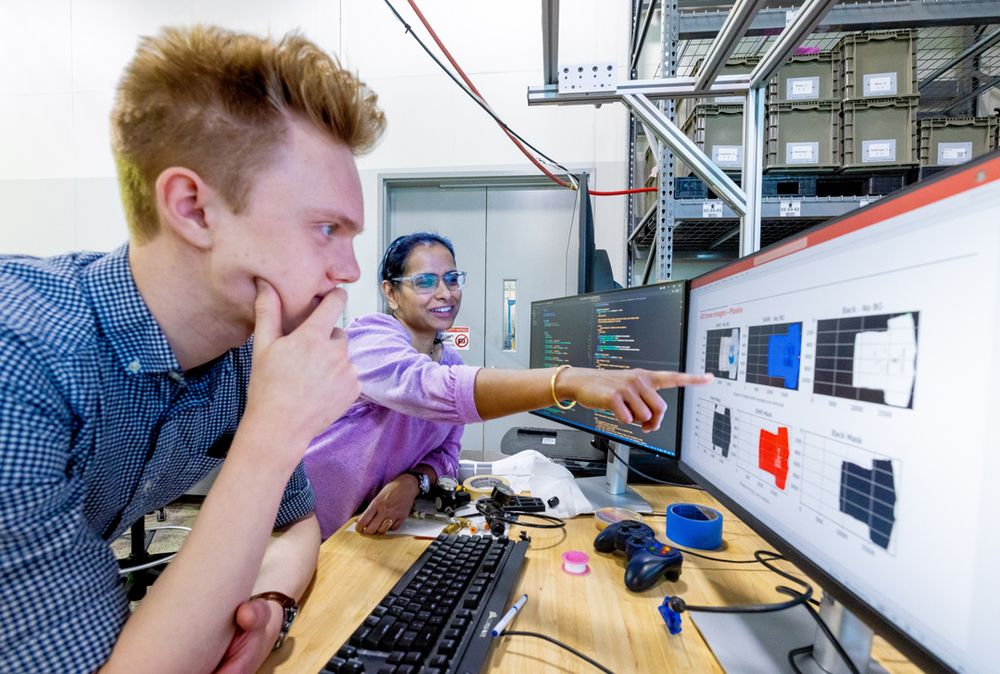 Two people are reviewing A I generated data on monitors