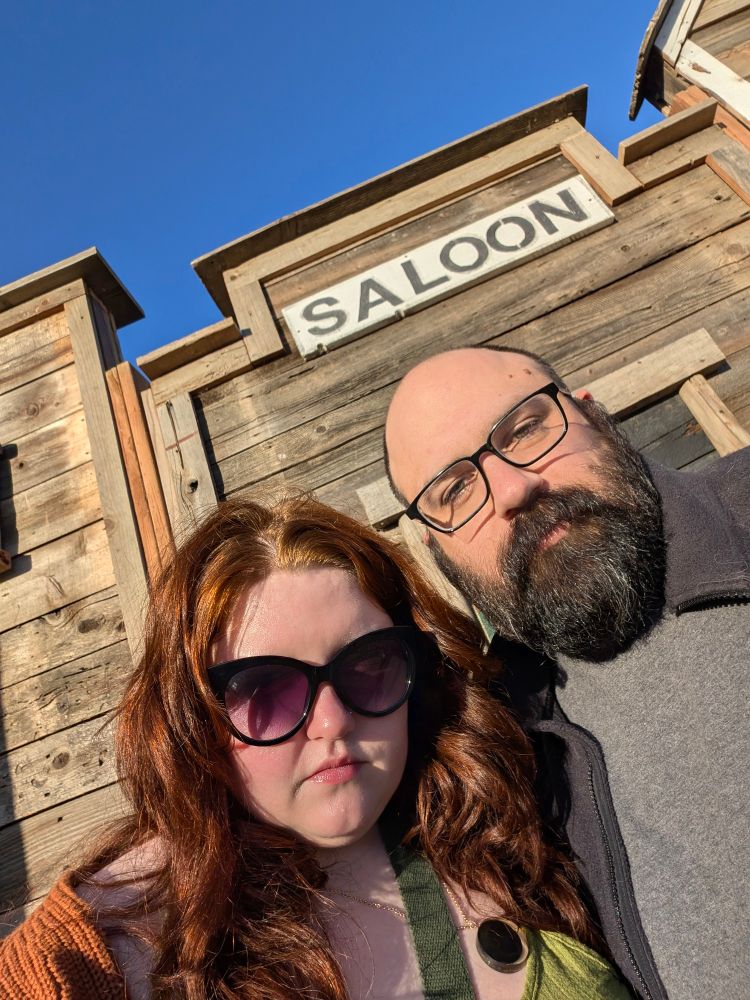 Cory and Thomas in front of a fake saloon building facade.