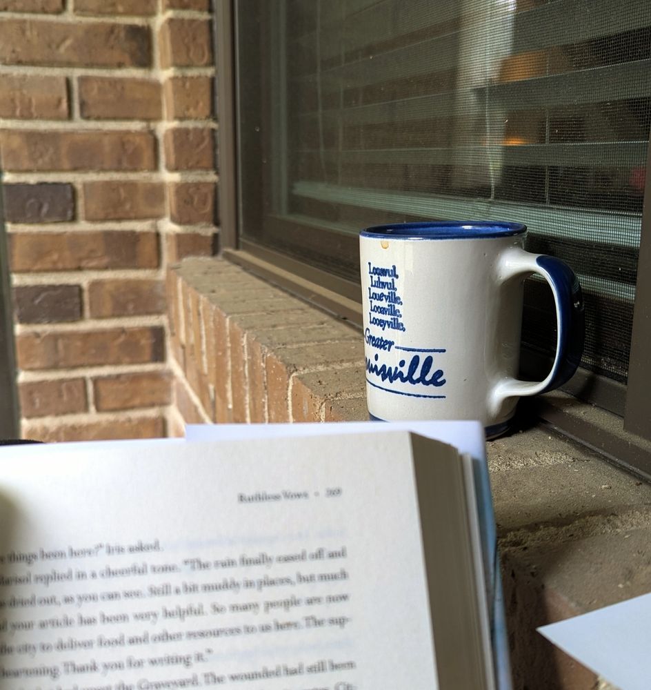 a blurred book page in the foreground with an in focus mug on a ledge behind it.