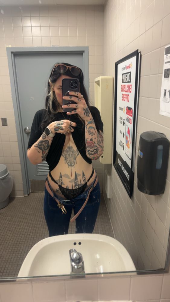 Woman with jeans unbuttoned and top pulled up, cleavage underneath showing postop breast augmentation and tummy tuck results