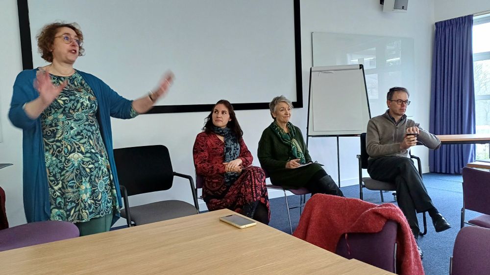 Photo of four academics in a panel on a University campus, three women and one man, speaking about research.