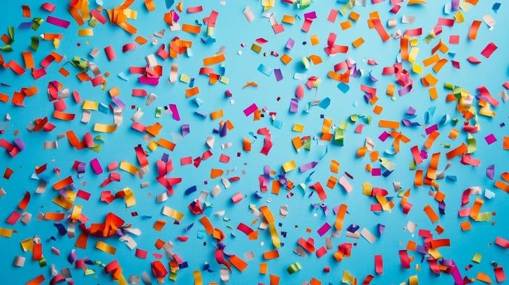 Photo of colourful confetti against a bright lighter blue background.