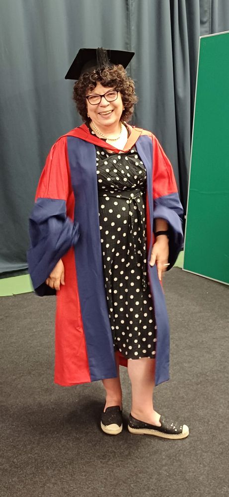Photo of Dr Marina Shapira wearing her graduation gowns and cap, smiling.