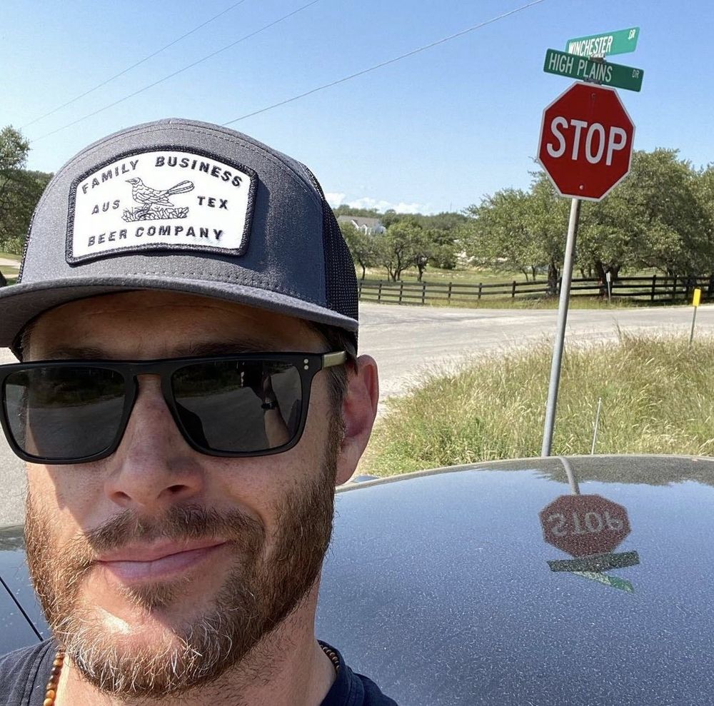 Jensen Ackles by a crossroad sign. One of the streets is named Winchester.