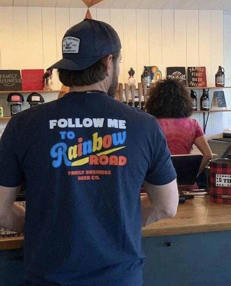 Jensen Ackles from behind, wearing a t-shirt that says “Follow me to Rainbow Road”