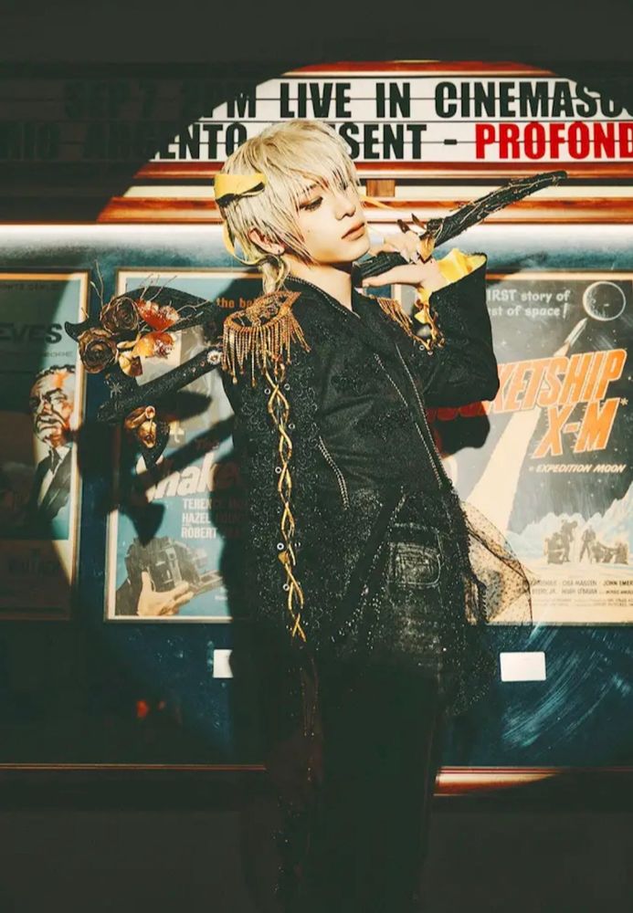 Haru styled in black and gold for their comeback. He’s got short blond hair and is wielding a floral decorated axe.