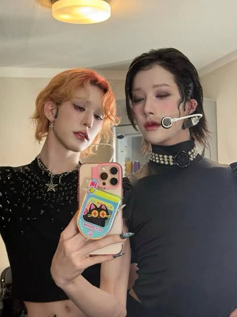 A Wumuti and Rui selca. They’re both wearing black tops- muti has rose gold colored hair, Rui with a black chin length bob
