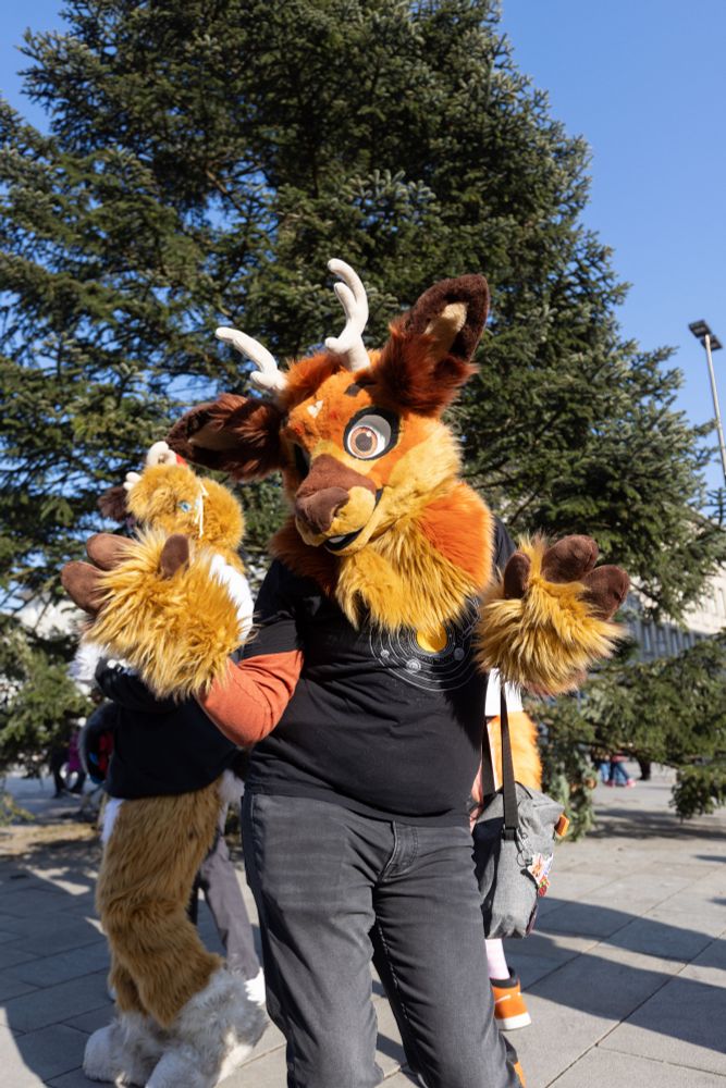 Me in my deer fursuit (sans the fur collar and bow) being blinded by the sun, though still trying to do a cheerful pose towards the camera.