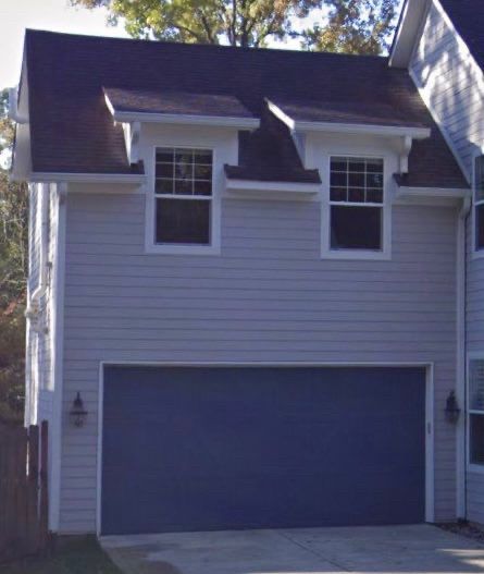 picture of a garage that has a double stall door and two windows above the door on a second story. it looks like a blocky human face.