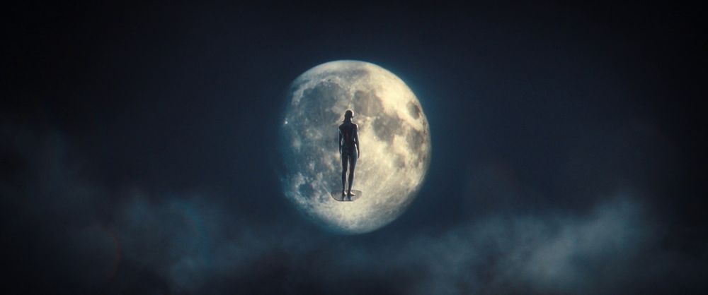 Screencap des "Quatre Fantastiques : Premiers pas" (2025), montrant le Surfer d'Argent flottant face à la Lune dans un plan très large.