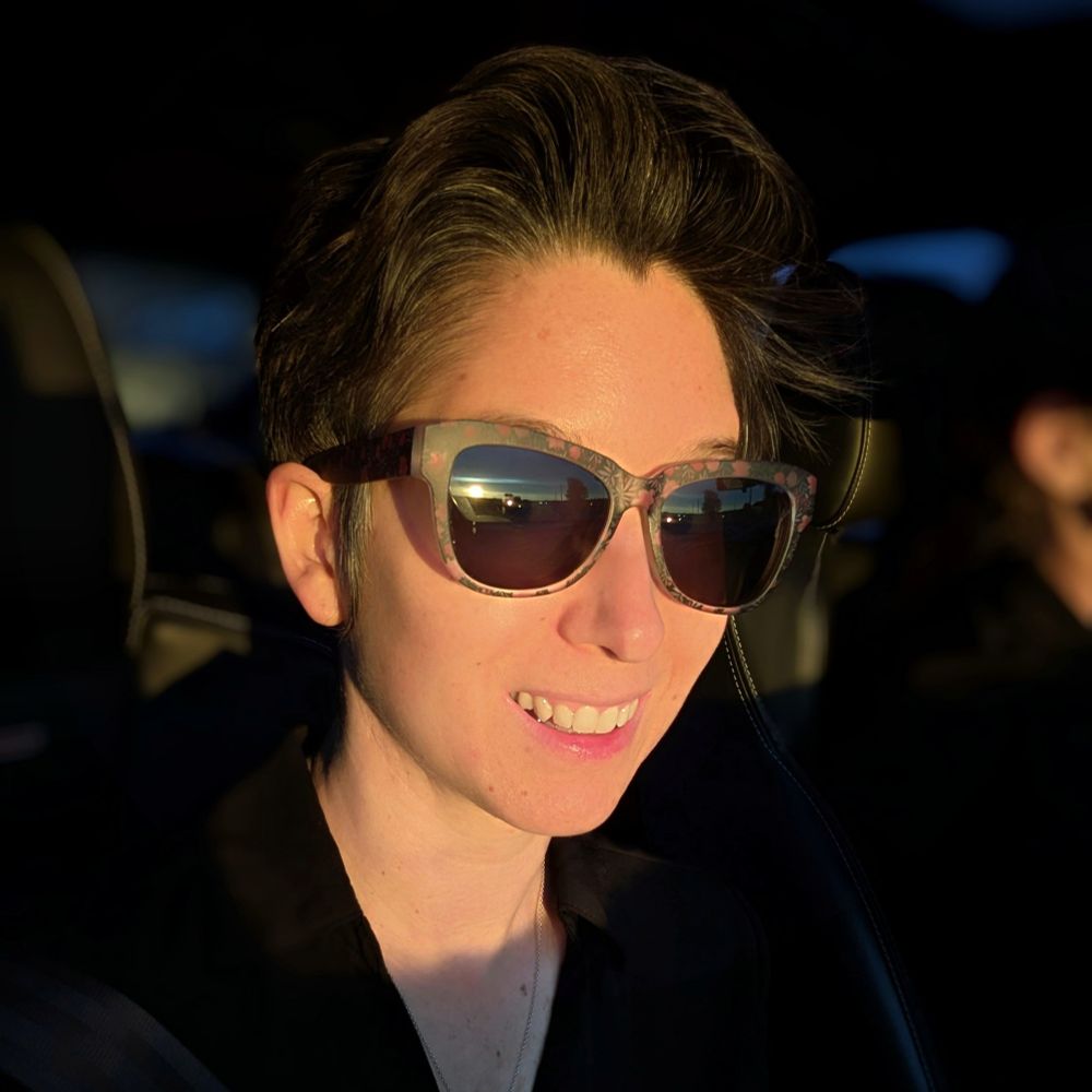 Selfie in the car using the great light of the setting sun. I'm wearing floral sunglasses and a black blouse.