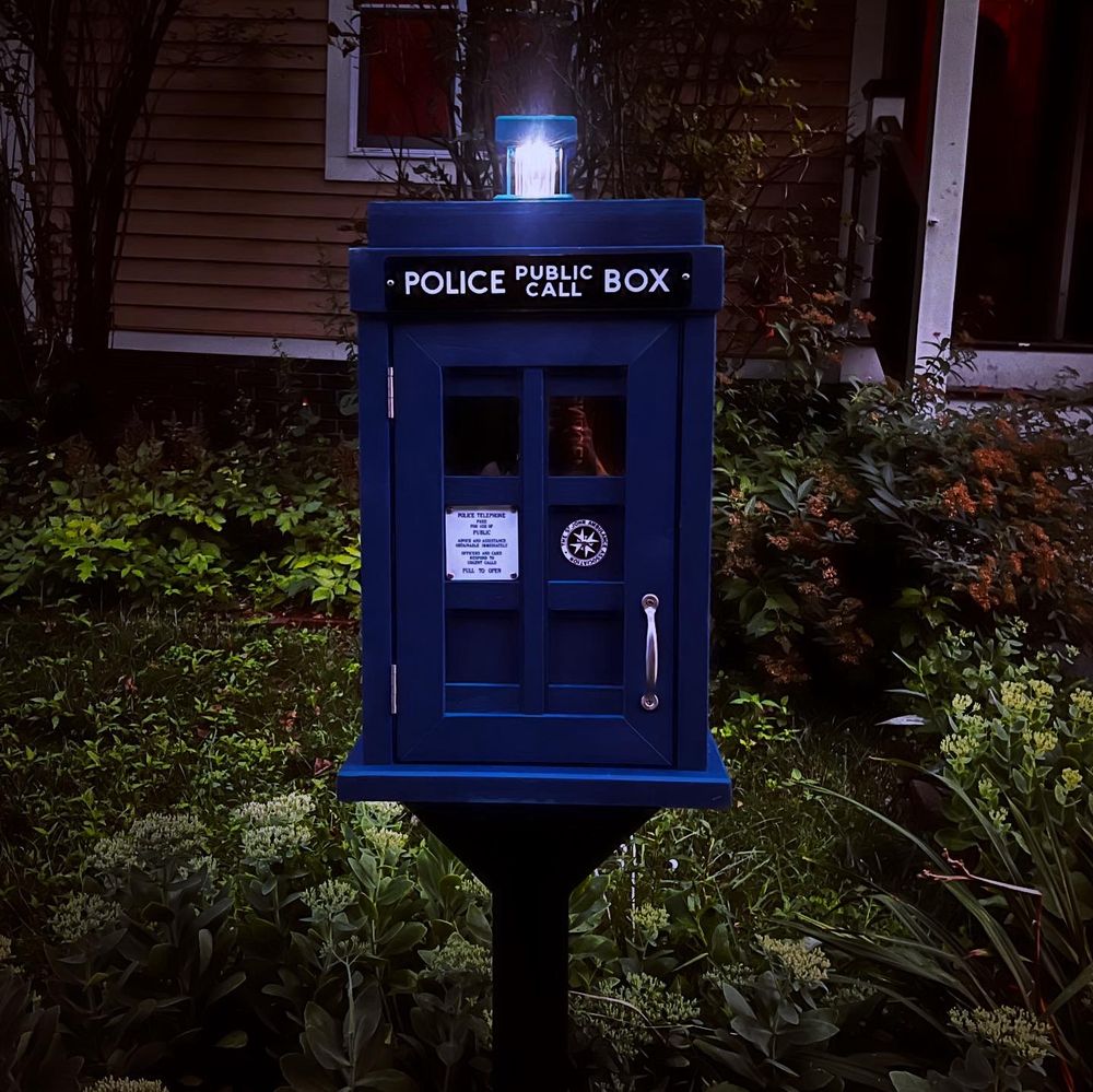 TARDIS little free library with light lit