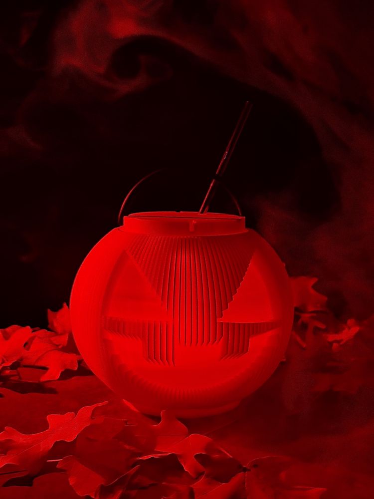 A spooky Jack o Lantern cocktail vessel. leaves and smoke surround.
