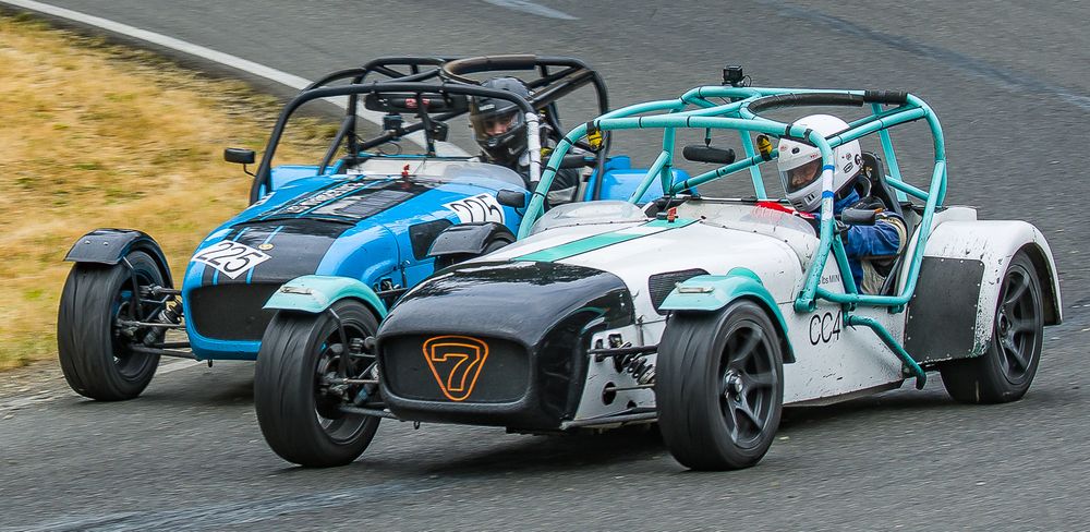Me driving a white Caterham Seven race car, going wheel-to-wheel with another Caterham on the track.