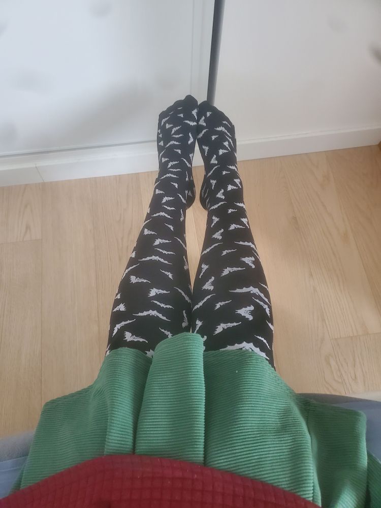 Photo de mes jambes avec mes beaux collants noirs à chauve-souris et ma jupe verte qui arrive aux genoux et le bas du pull 