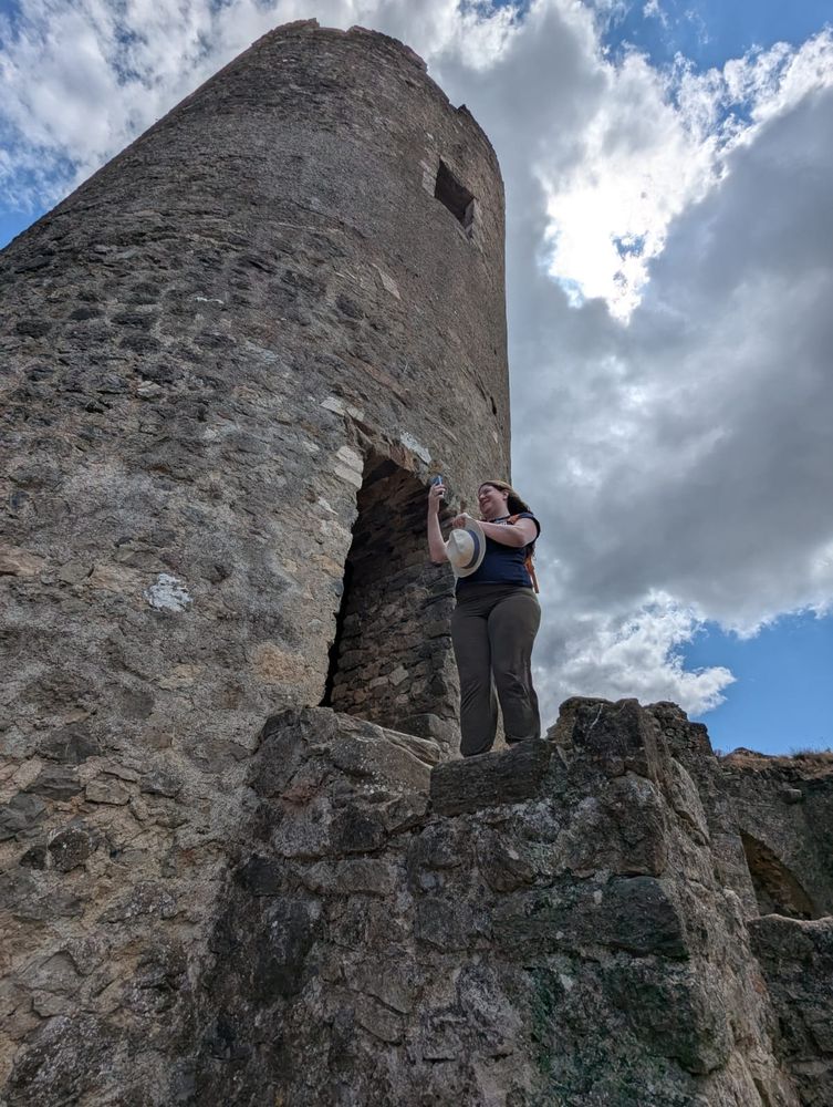 Photo de moi debout au pied d'une grande tour en pierre vue en contre plongée