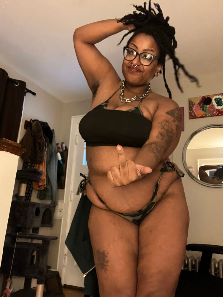 Photo of Lilith bear in a camo bikini and black crop top making a middle finger at the camera 