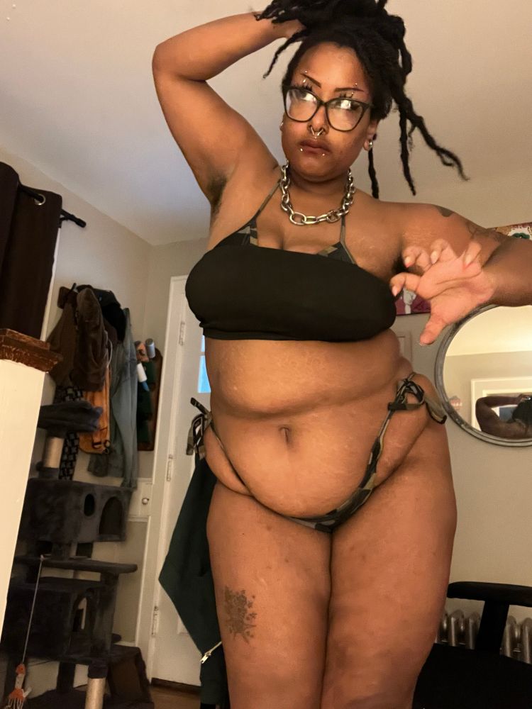 Photo of Lilith bear in a camo bikini and black crop top making a claw motion at the camera 