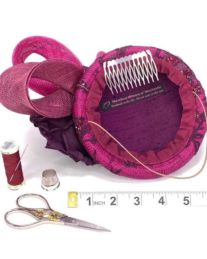 View of the underside of the fascinator hat showing the silk lining, metal comb and millinery elastic for a secure and comfortable fit. Scissors, thimble and thread nearby illustrate the careful construction and studio craftsmanship involved.