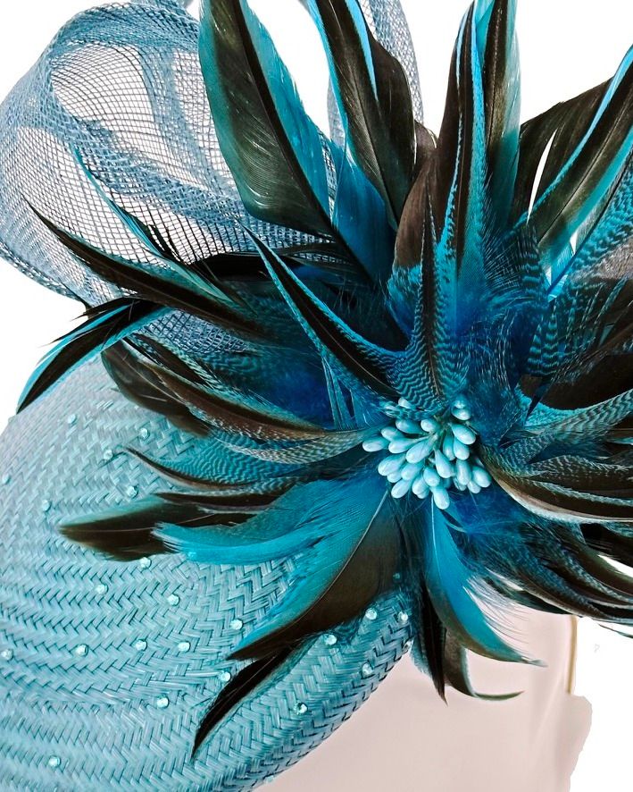 Close-up of handcrafted feather flower in teal and blue-black tones with tonal bead centrepiece and crystal embellishments.