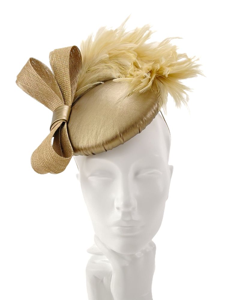 Bronze-gold perching pillbox wedding hat with satin-effect bow and blonde feathers, displayed on a white mannequin. Ideal for the Mother of the Bride and Mother of the Groom at a Christmas or winter wedding in Hampshire.