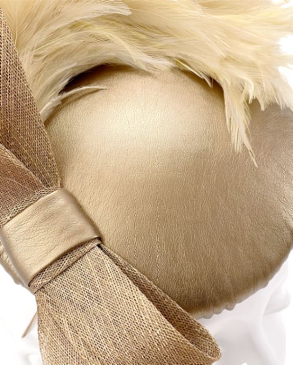 Close-up photograph highlighting the texture of the bronze-gold leatherette base, hand-finished tying of the bow and soft feathers. Designed for elegant winter weddings and special occasions.