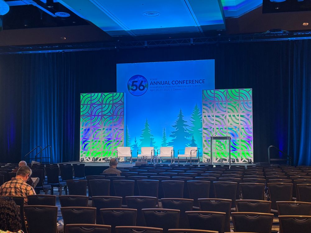 A quietly lit stage ahead of a busy conference day, with a mass of audience chairs lined up neatly.