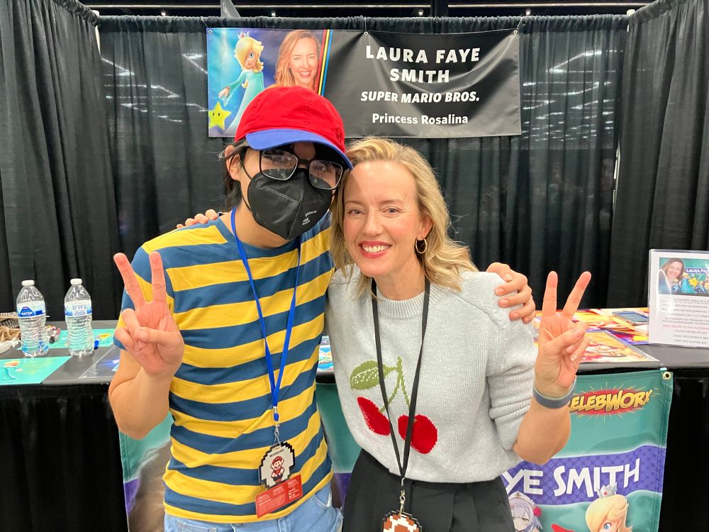 A picture taken of me and Laura Faye Smith, the English voice of Princess Rosalina (since Super Mario 3D World) in the Super Mario series, both holding up peace signs and smiling brightly.