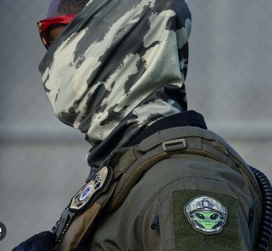 Another masked ICE agent, wearing a balaclava