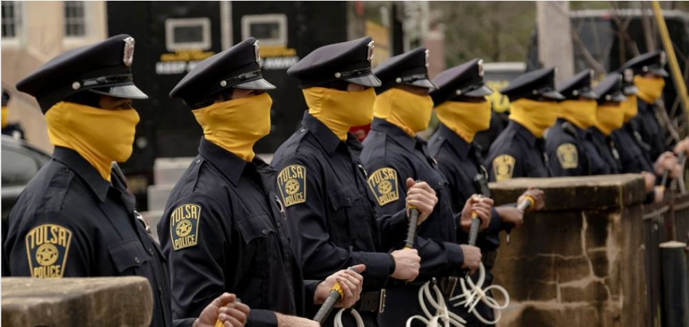 Still from The Watchmen, with a line of cops using masks t cover their faces.
