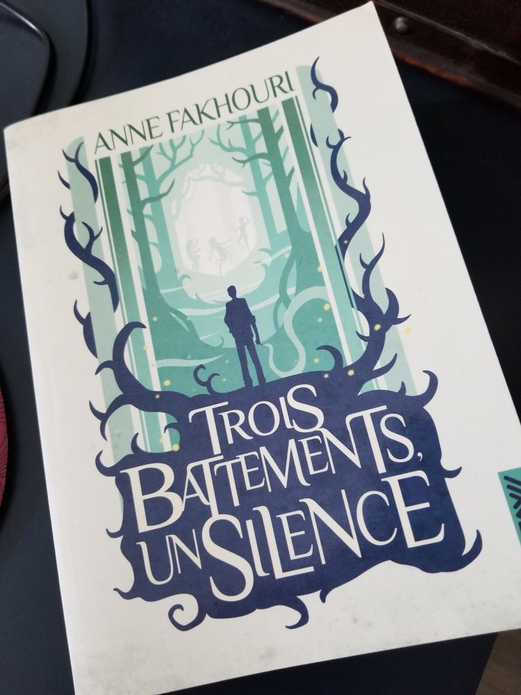 Couverture de Trois battements, un silence. On distingue une silhouette d'homme debout face à un bois, tout entouré de ronces. En arrière-plan, dans un halo de lumière, dansent trois silhouettes de fées.