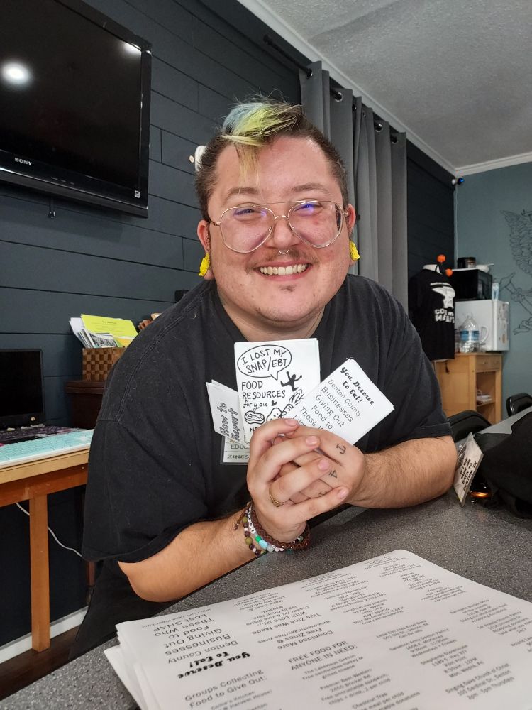 Me with three zines in my hand, two are SNAP help zines and one is how to report ICE